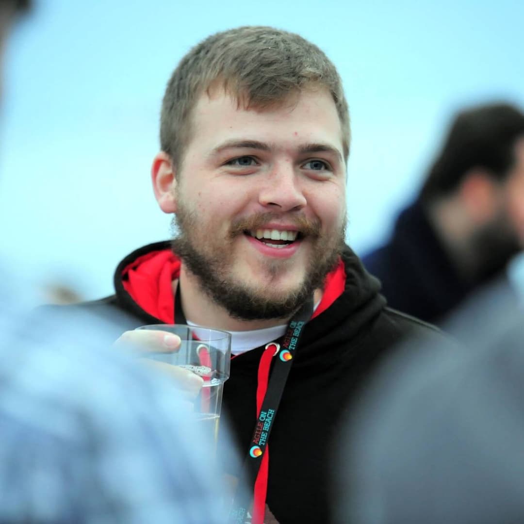 Daniel stood at a conference, smile on his face and beer in hand